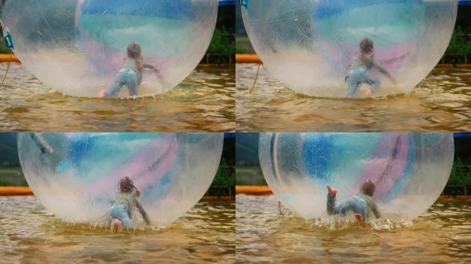 小女孩在池塘里的大水球里爬行很开心