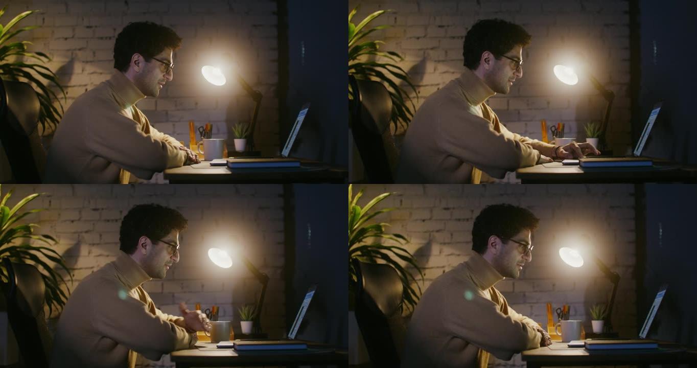 一个年轻人坐在笔记本电脑前的桌子旁，正在视频链接上聊天