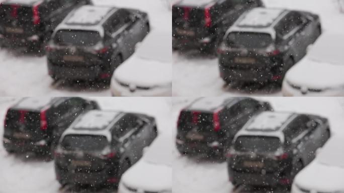 阴天，缓慢的雪落在停放的汽车的模糊背景上，有选择性的焦点