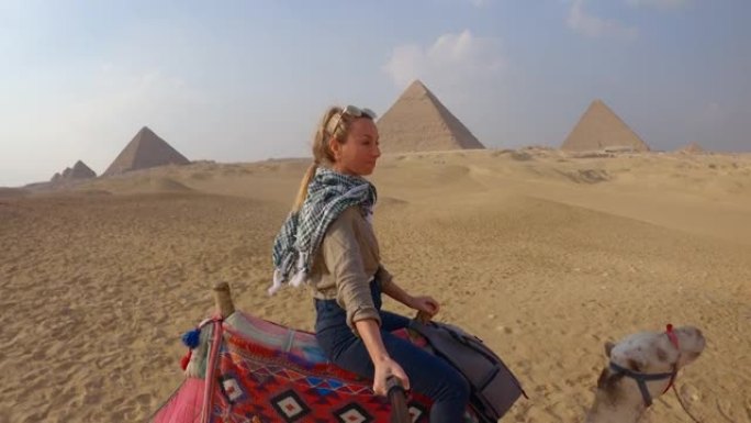 年轻女子在埃及骑骆驼时自拍。女性观光骆驼上的大金字塔自拍很酷