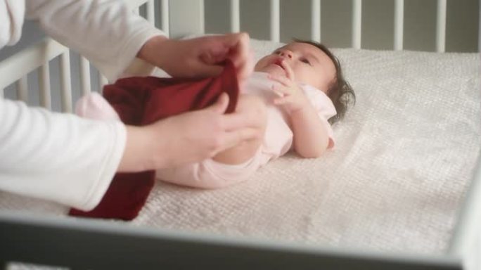 有爱心的母亲将一个躺在婴儿床上的新生女婴打扮成婴儿床。