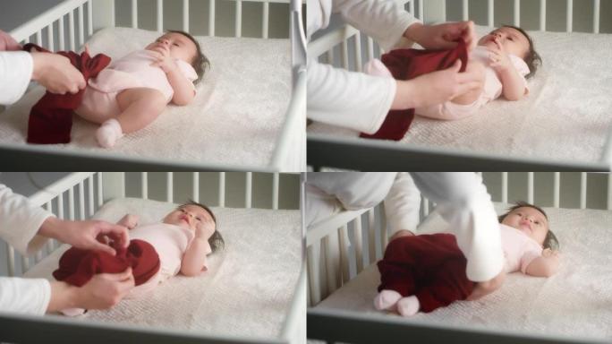 有爱心的母亲将一个躺在婴儿床上的新生女婴打扮成婴儿床。