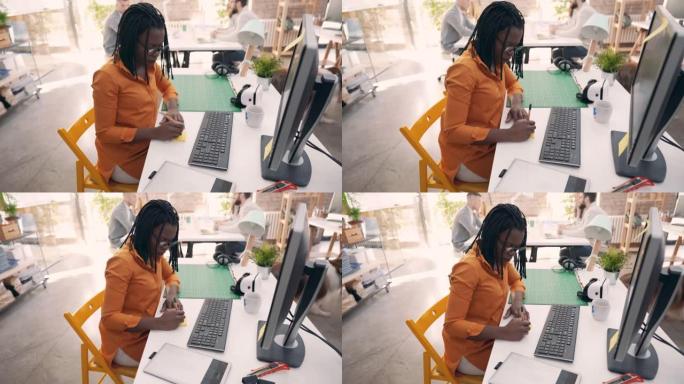 在开放空间办公室工作的黑人女企业家，在笔记本电脑上工作