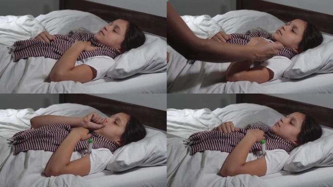 9岁小女孩的特写镜头感冒躺在床上患流感。小孩咳嗽和打喷嚏，母亲的手检查她的体温，抚摸额头。4K