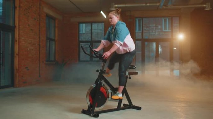 运动女子骑在雾霾健身房锻炼固定自行车训练程序，室内减肥