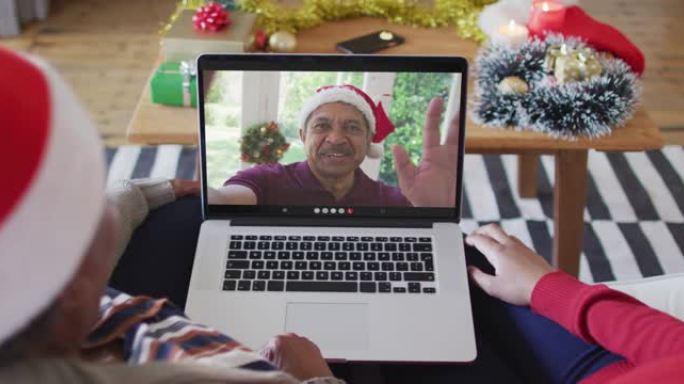 非裔美国母亲和女儿使用笔记本电脑与屏幕上的男人进行圣诞节视频通话