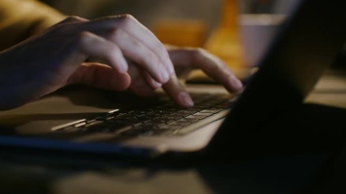 年轻皮肤白皙的男人坐在灯旁在笔记本电脑上打字