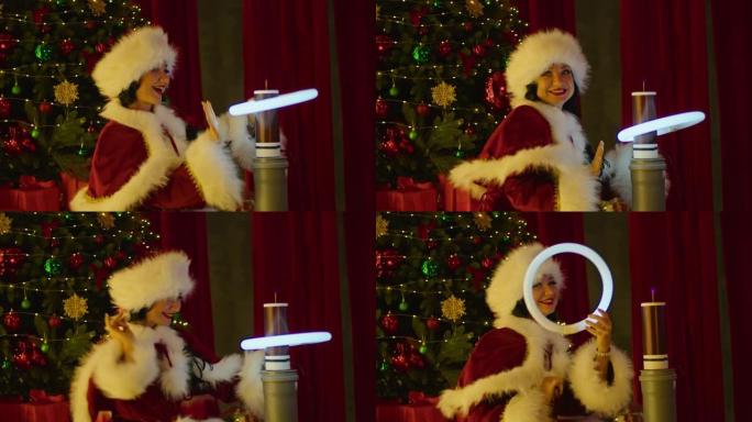 圣诞老人服装中的幸福女人在圣诞树的背景下，在特斯拉线圈附近玩霓虹灯管。新年秀，儿童假期。
