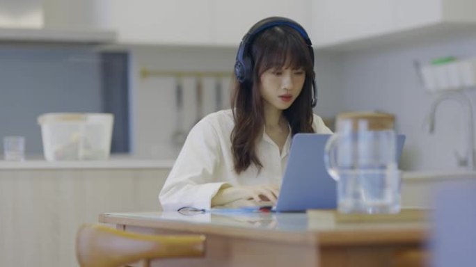 年轻的亚洲女商人使用笔记本电脑与同事谈论视频通话中的计划，同时在客厅在家工作。
