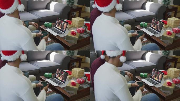 带有圣诞老人帽子的混血儿父子使用笔记本电脑与家人在屏幕上进行圣诞节视频通话