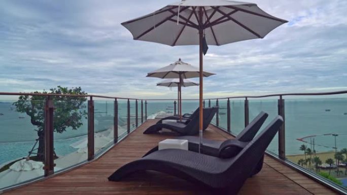 带雨伞的床池周围有海洋背景的游泳池-假日和度假概念