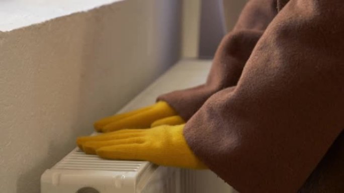 戴手套的女人在家里结冰，检查散热器是否温暖