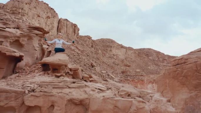 瑜伽中的女人在美丽的红色沙漠峡谷和山脉周围摆姿势