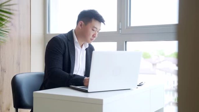 在办公室工作时坐在电脑或笔记本电脑上工作的亚洲商人的剪影