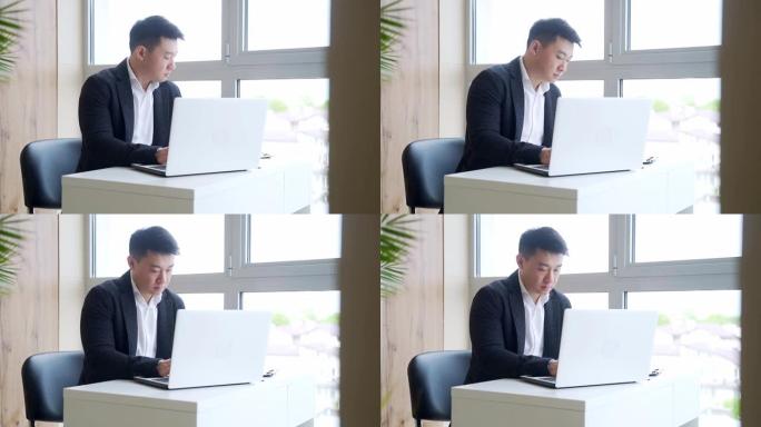 在办公室工作时坐在电脑或笔记本电脑上工作的亚洲商人的剪影