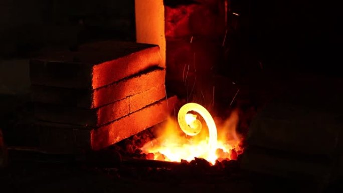 铁匠在锻造中工作，在火中加热金属。用铁匠铺制作金属制品。火焰中的红色热铁片已准备好进一步加工。
