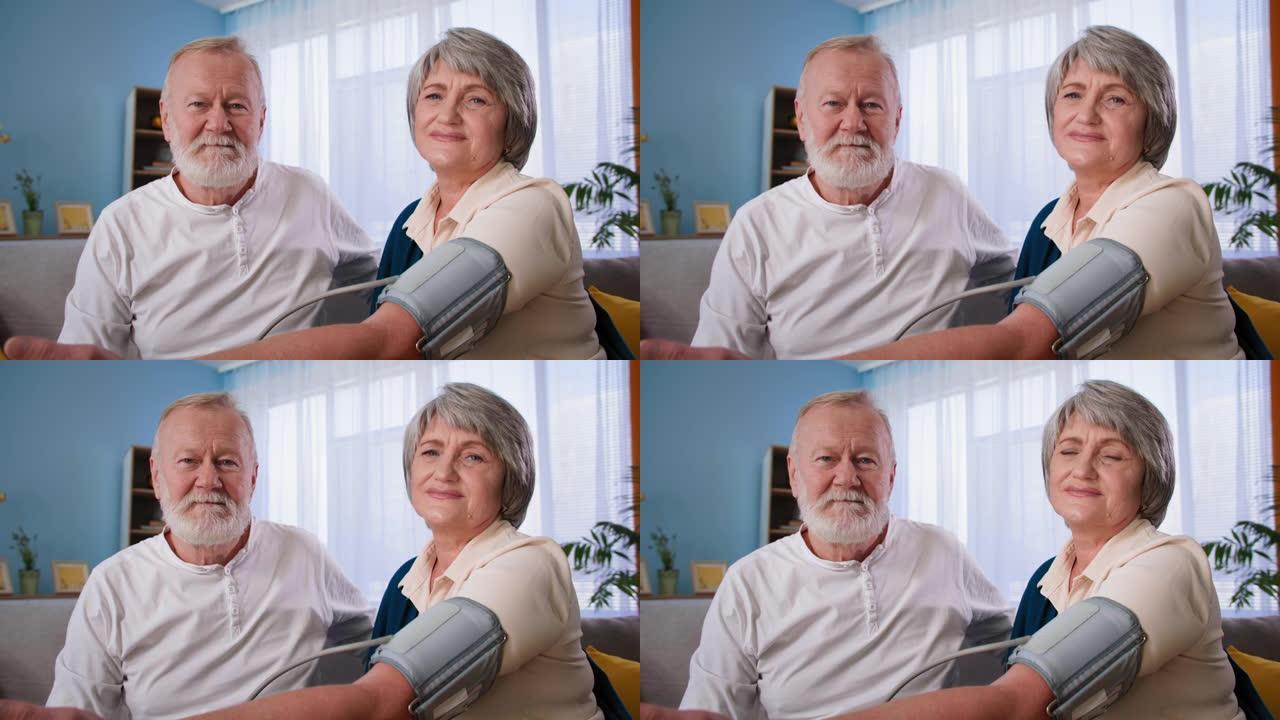 老年夫妇在测量血压时看着相机，在家中用眼压计肖像祖父母