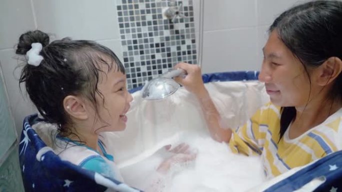 快乐的亚洲孩子们在塑料浴缸里对着姐姐的脸吹泡泡，一起大笑，生活理念。