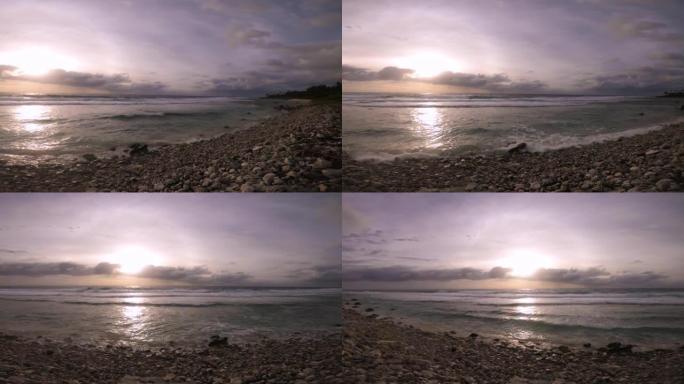在平静宁静的日落日，金属深绿色蓝色透明泻湖与珊瑚岩石海滩的旋转水平视图俯瞰附近的海洋海浪喷雾旋转漂移
