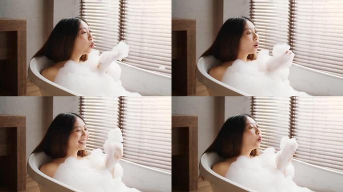 美丽的亚洲女人吹泡沫，而在家里洗热水澡
