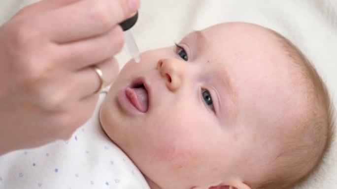 小男孩从吸管服用维生素d的特写镜头。新生儿保健和疫苗接种的概念