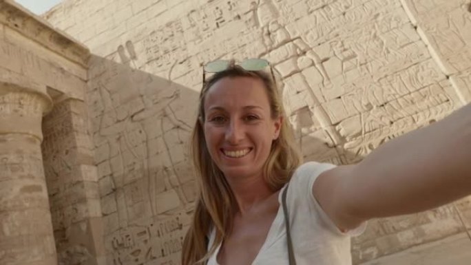 年轻女子在卢克索观光古埃及神庙拍摄酷自拍