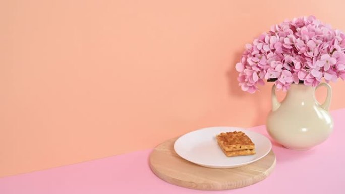 甜点华夫饼配一杯咖啡，以鲜橙色粉色为主题，花瓶里有春天的花朵。停止运动