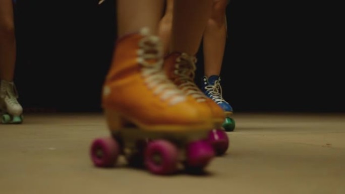 穿着旱冰鞋的女性腿，在地板上的旱冰鞋公园快速滑冰。年轻女性的特写腿是专业滑冰。不同种类的彩色老式滚筒