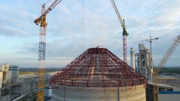 工业生产区高混凝土厂房结构和塔式起重机在建水泥厂的鸟瞰图。制造与全球工业概念