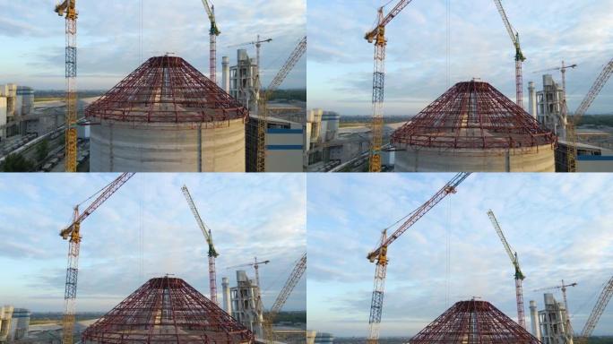 工业生产区高混凝土厂房结构和塔式起重机在建水泥厂的鸟瞰图。制造与全球工业概念