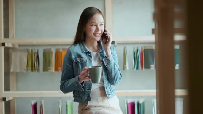 亚洲女性创意设计师项目通过智能手机对话与客户讨论和展示，亚洲休闲布放松与客户或朋友交谈手持智能手机和