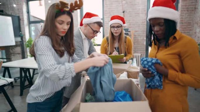 在办公室，有爱心的现代多种族商人为圣诞节捐款打包衣服