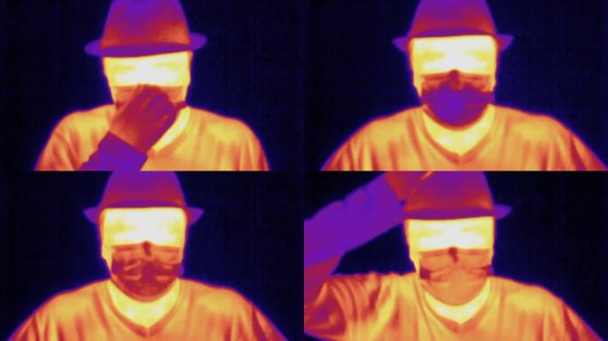 紫外光谱热成像相机。戴帽子的男人，戴上防护医用口罩，看热像仪和手势你好。检测体温升高的Covid大流