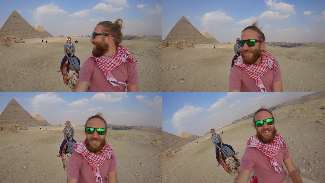 年轻夫妇在埃及骑骆驼时自拍。夫妇在骆驼上观光大金字塔，自拍很酷