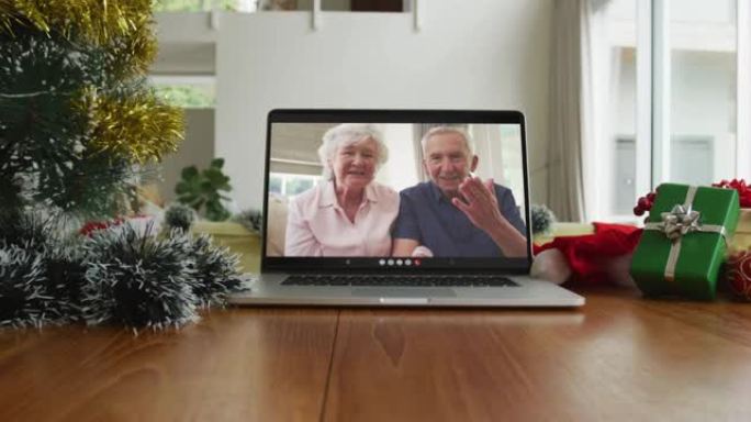 微笑的高加索高级夫妇在笔记本电脑上的圣诞节视频通话中挥手