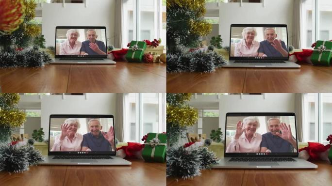 微笑的高加索高级夫妇在笔记本电脑上的圣诞节视频通话中挥手