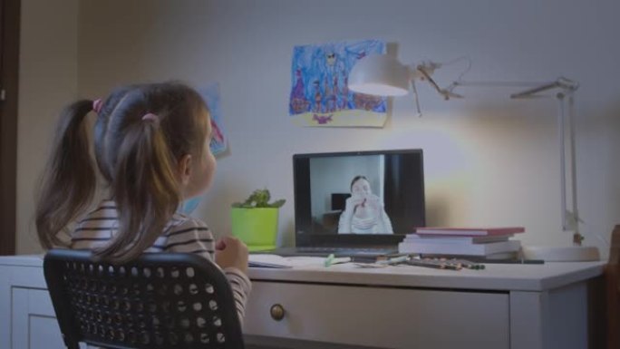 学龄前女孩，一个带着老师在笔记本电脑上在线学习字母的孩子，在线远程学习，在家中的虚拟视频会议课程中与