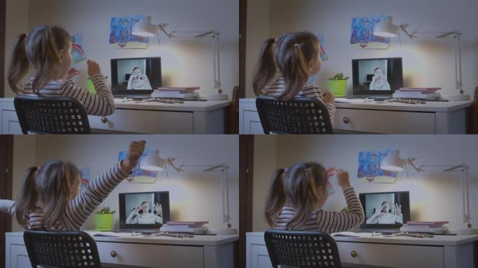 学龄前女孩，一个带着老师在笔记本电脑上在线学习字母的孩子，在线远程学习，在家中的虚拟视频会议课程中与