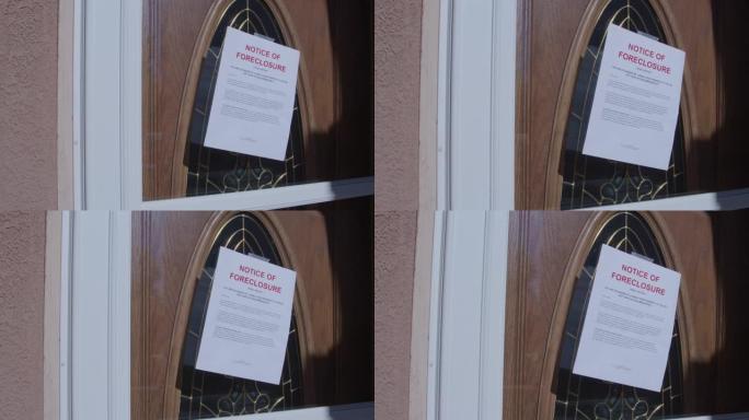 手持照片，贴在郊区居民区房屋的玻璃前门上的纸质止赎通知