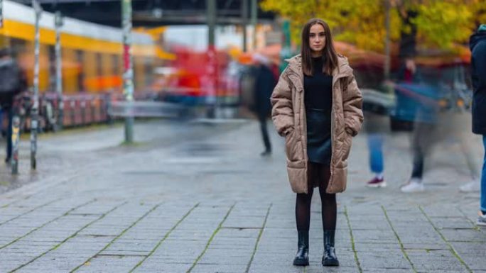 秋日站在城市街道上的年轻女子独自看着相机的时间流逝。现代生活方式、人和社会观念。