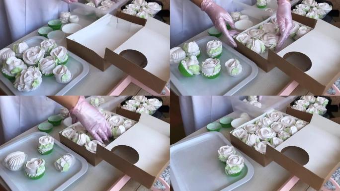 一个戴着橡胶手套的女人把自制的棉花糖放在工艺盒里。在她面前的桌子上是各种形状和大小的棉花糖。加速射击