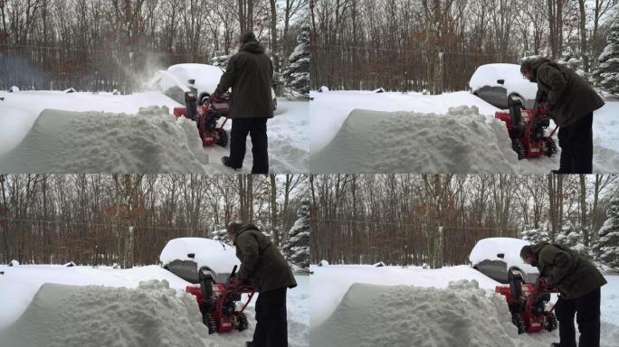 一名男子在冬季暴风雪后清理了被雪覆盖的汽车周围的车道，启动了现在的吹瓶机
