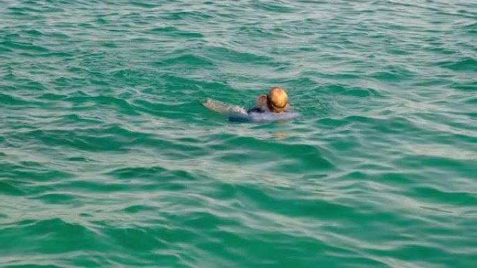 一个穿着衬衫，领带和袜子的有趣男人在阳光明媚的日子在海里游泳。慢动作，4k