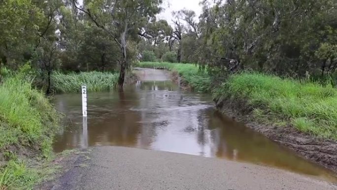 一条被洪水淹没的河流流过一条乡村土路上的桥梁