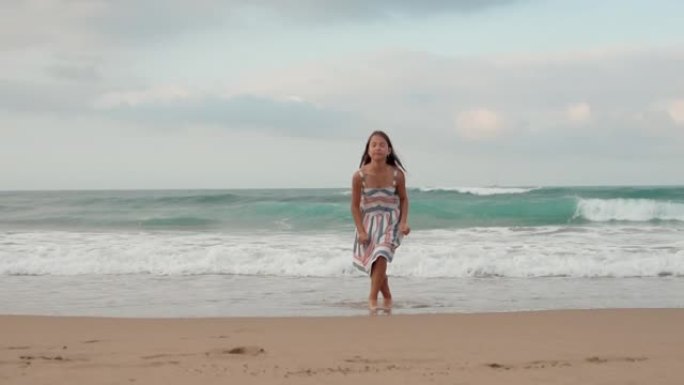 微笑的女人在海岸线享受假期。快乐的女孩在海边跳舞。