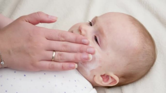 母亲用医用乳霜治疗新生儿有问题的皮肤。新生婴儿卫生、健康和皮肤护理的概念