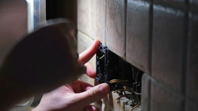 电工在黑暗中修理公寓的电源插座。静态镜头。家居装修概念