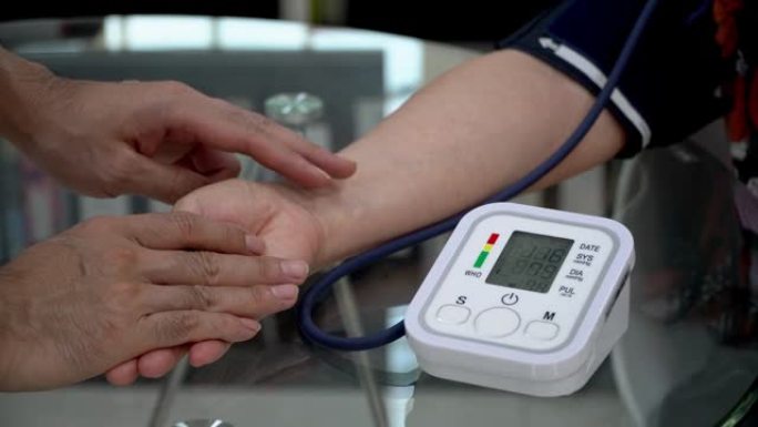 医生检查老年女性患者动脉血压。卫生保健。使用上臂血压监测器监测患者的血压