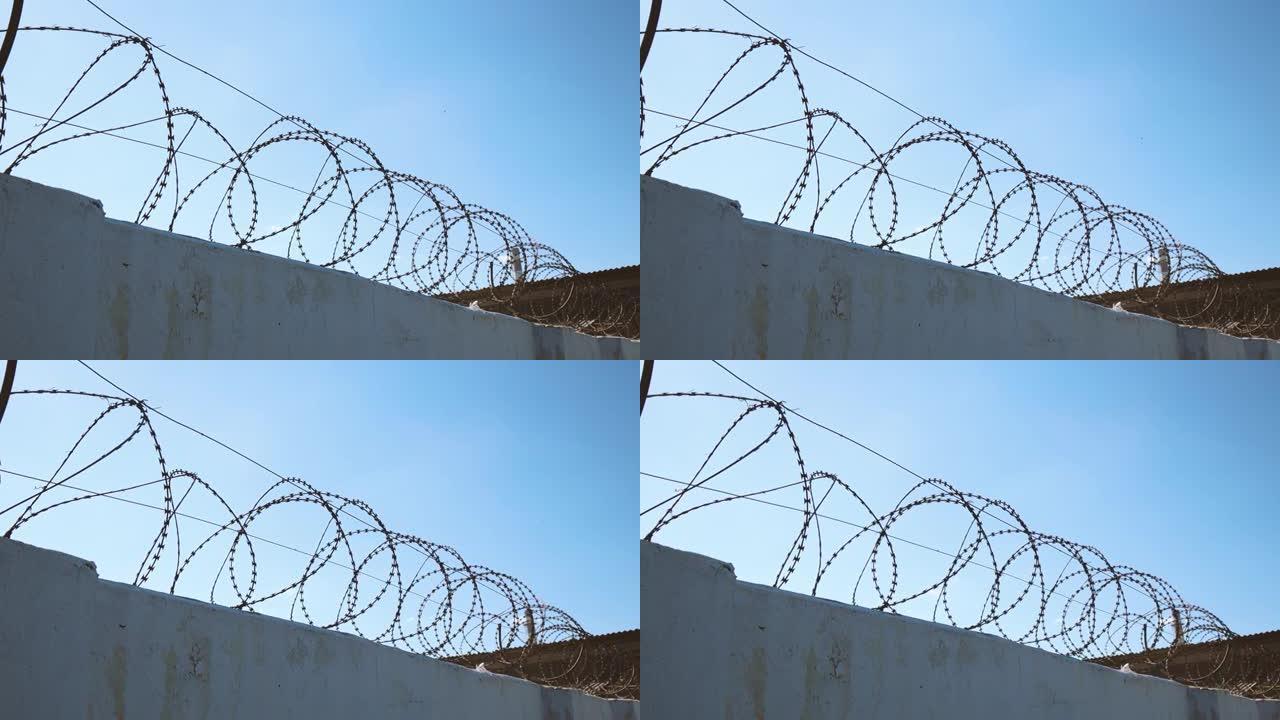 带倒刺铁丝网的混凝土墙阻止移民。监狱的概念。倒钩铁丝安全边界。