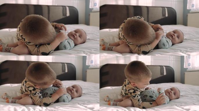 一个小男孩和他的弟弟一起玩。可爱的男孩抱着他刚出生的小弟弟。幸福家庭的概念。
